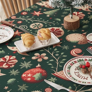 Detailed view of dark green Christmas tablecloth featuring red baubles and white snowflakes