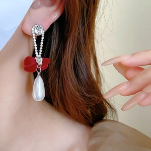 Detail of a red velvet bow earring with rhinestones and a large teardrop pearl