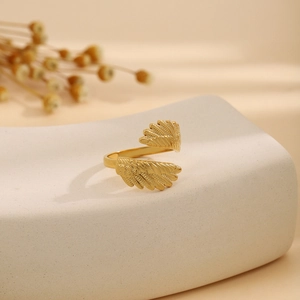 Close-up of a gold-plated stainless steel feather ring on a white display stand