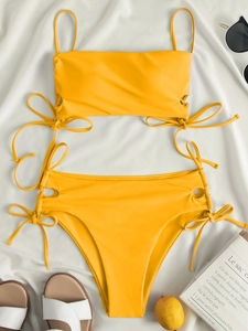 Flat lay of yellow high waist bikini with side drawstring details and summer accessories
