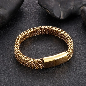Detail of golden woven chain bracelet featuring a magnetic clasp on textured dark stone