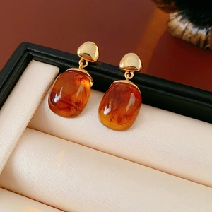 Detailed view of 18K gold plated resin earrings with amber gemstones in a gift box