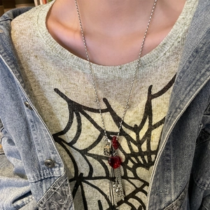Detail of Y-shaped necklace featuring red heart, polka dot cube, and metal tassel