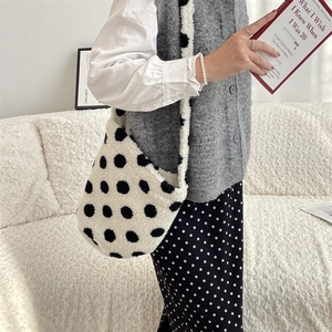 Polka dot plush bucket bag styled with a gray sweater vest in a cozy home setting