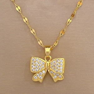 Vue macro du collier avec pendentif nœud doré et cristaux blancs étincelants