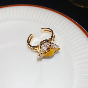 Detailed top view of gold adjustable ring with amber square stone and pearls on ceramic plate