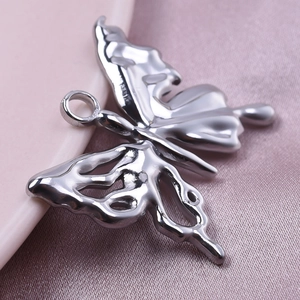 Detailed view of silver 304 stainless steel butterfly pendant on pink fabric background