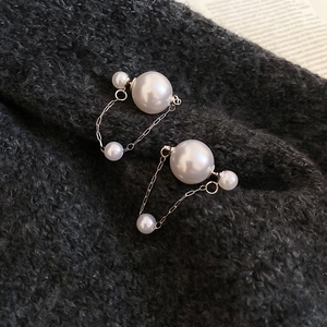 Detailed view of silver drop earrings with double white pearls and elegant link chains