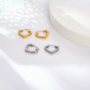 Detailed view of heart-shaped bamboo texture hoop earrings in gold and silver finish
