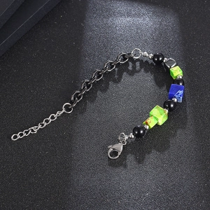 Titanium steel bracelet with black beads and blue-green cubic stones on textured background