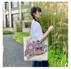 Close-up of canvas tote bag featuring detailed colorful owl and floral embroidery art
