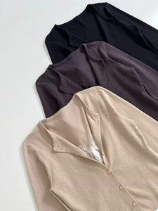 Detail view of stacked knit cardigans in black, grey, and beige with delicate lace trim