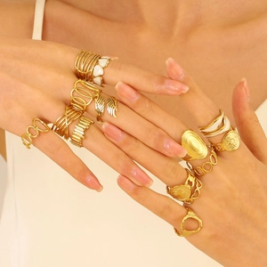 Detail of stacked gold irregular rings featuring wing and geometric chain designs