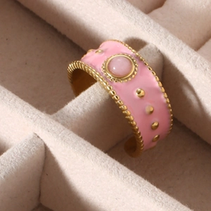 Detailed close-up of a pink enamel wide band ring set with a gemstone in a jewelry box