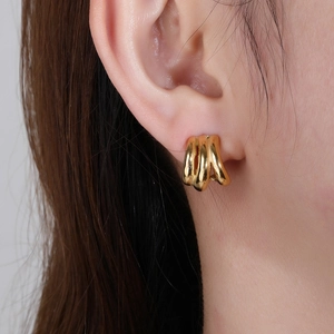 Minimalistische dreilagige Titanstahl-Ohrringe mit 18K Gold-Finish am weiblichen Model