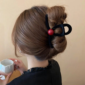 Detail of red bead on black flocked shark hair clip styled in a low bun hairstyle