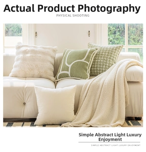 Close-up of cream textured sofa pillow covers and soft knit blanket in a cozy room