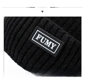 Detailed macro view of the knitted texture and FUMY logo label on the black winter beanie