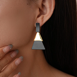 Détail de la boucle d'oreille géométrique avec des éléments noirs et dorés minimalistes