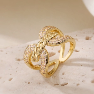 Intertwined 18K gold plated knot ring with sparkling zircon stones on white rock base