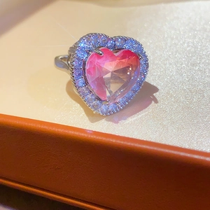 Close-up of heart-shaped pink gemstone ring with white zircon halo on a silver band