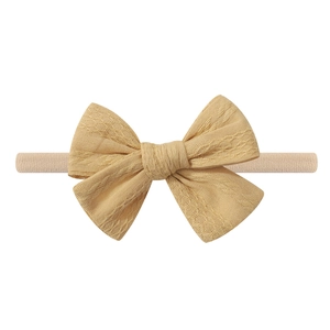 Detail shot of a beige textured fabric bow headband with high-elastic band for kids