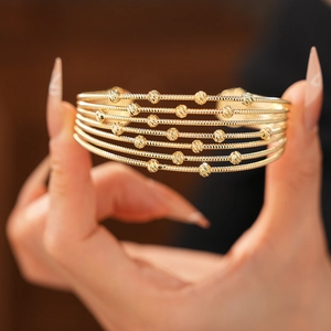 Détail d'un bracelet manchette doré à 6 rangs avec perles en métal gravées