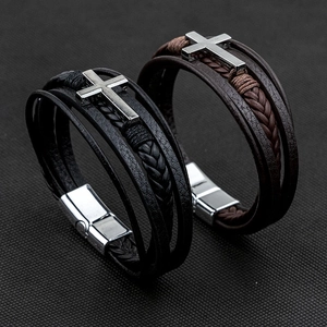 Detail of multi-layer braided leather bracelets with silver cross charm and magnetic clasp