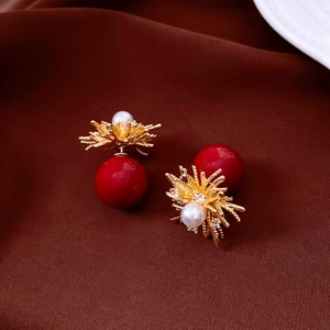 Detailed view of 18k gold-plated floral earrings with pearls and red beads