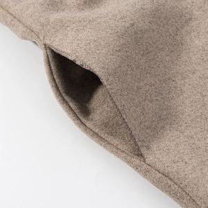 Detailed macro view of the camel wool blend fabric and stitched pocket of the coat