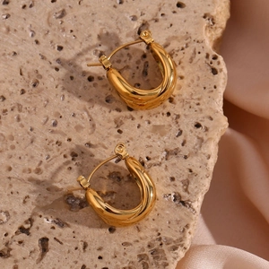 Macro detail of polished 18K gold plated stainless steel hoops on stone and silk