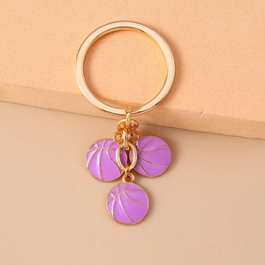 Detail shot of golden basketball keychain pendants with purple enamel finish on soft background