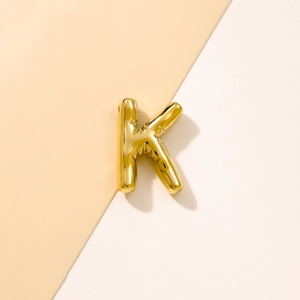 Macro view of a 3D bubble style golden letter K pendant with high polished metal finish