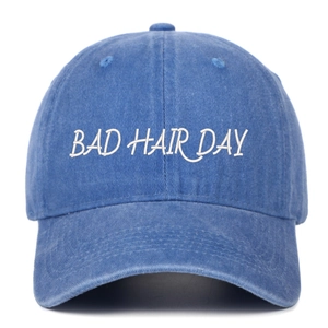 Gros plan de la broderie blanche BAD HAIR DAY sur la casquette de baseball en jean délavé