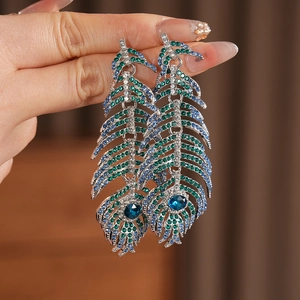 Macro shot of silver feather earrings with multi-color rhinestones and blue crystals