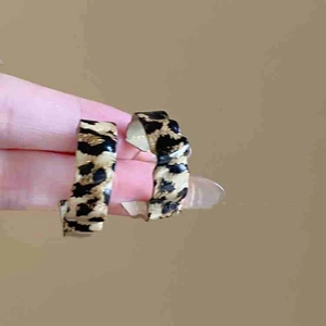 Detail shot of C-shaped leopard print earrings with a glossy finish and fashion design