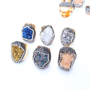 Macro detail of various colorful druzy quartz rings with sparkling crystal pavé edges