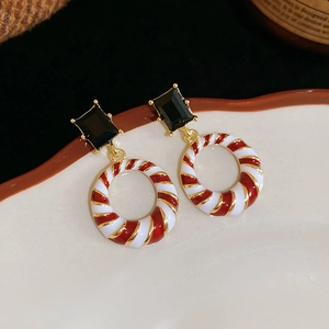 Detail of Christmas style enamel drop geometric earrings on a white porcelain dish