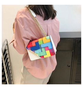 Detail shot of a crossbody bag featuring colorful geometric patchwork and a gold chain strap