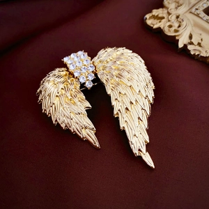 Broche ailes vintage dorée avec strass blancs sur fond en velours rouge foncé