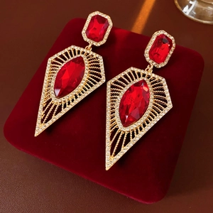 Detailed macro view of vintage gold earrings with large red gemstones and pavé crystals