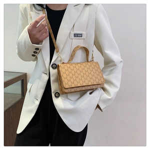 Classic brown monogram letter print handbag shown styled with a white blazer