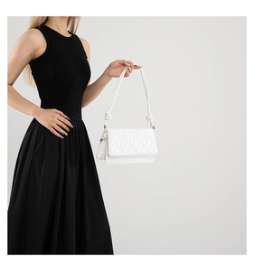 Close-up of white quilted leather texture and knotted shoulder strap on small square bag