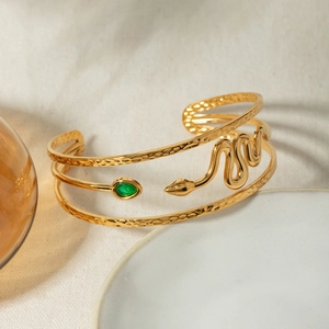 Detailed macro of a 18k gold stainless steel snake cuff with a green teardrop stone
