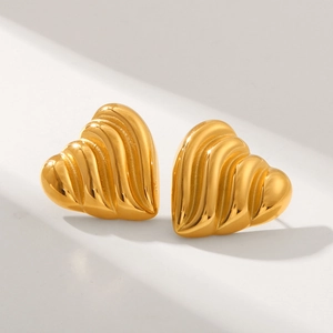Macro detail of 18k gold heart studs with textured ridges on white background