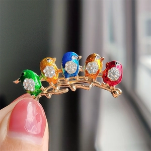 Detail of colorful enamel bird brooch with sparkling rhinestones on a metal branch