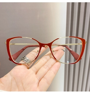 Detail of stylish red cat-eye glasses frame with sleek gold metal temples held in hand