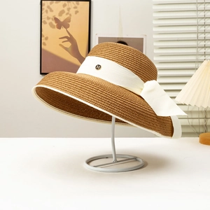 French Hepburn style brown straw sun hat with wide brim and white ribbon bow detail