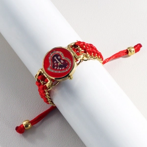 Macro detail of red heart-shaped dial and woven bracelet strap on women's gold watch