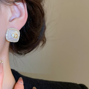 Close-up of vintage square earrings with CD logo, pearls and pavé diamonds on model